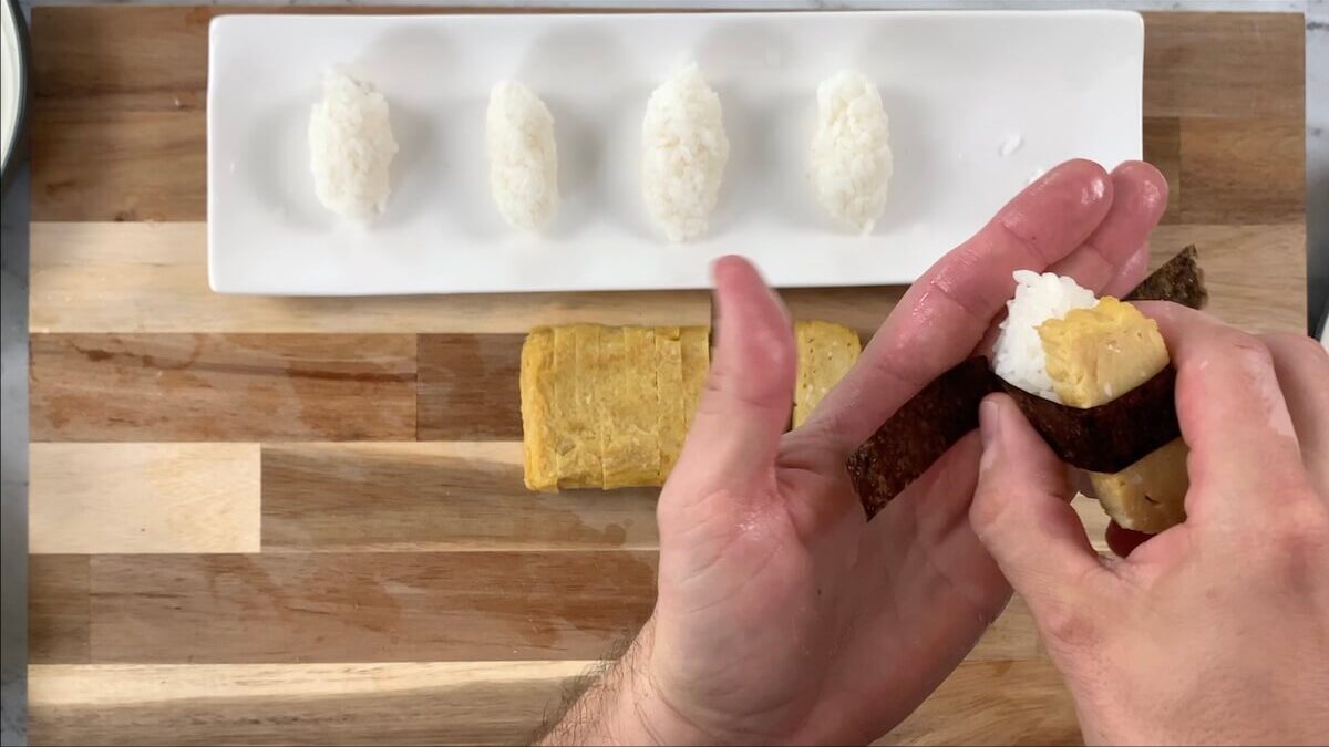 Wrap the nori strip around the tamagoyaki and rice ball.