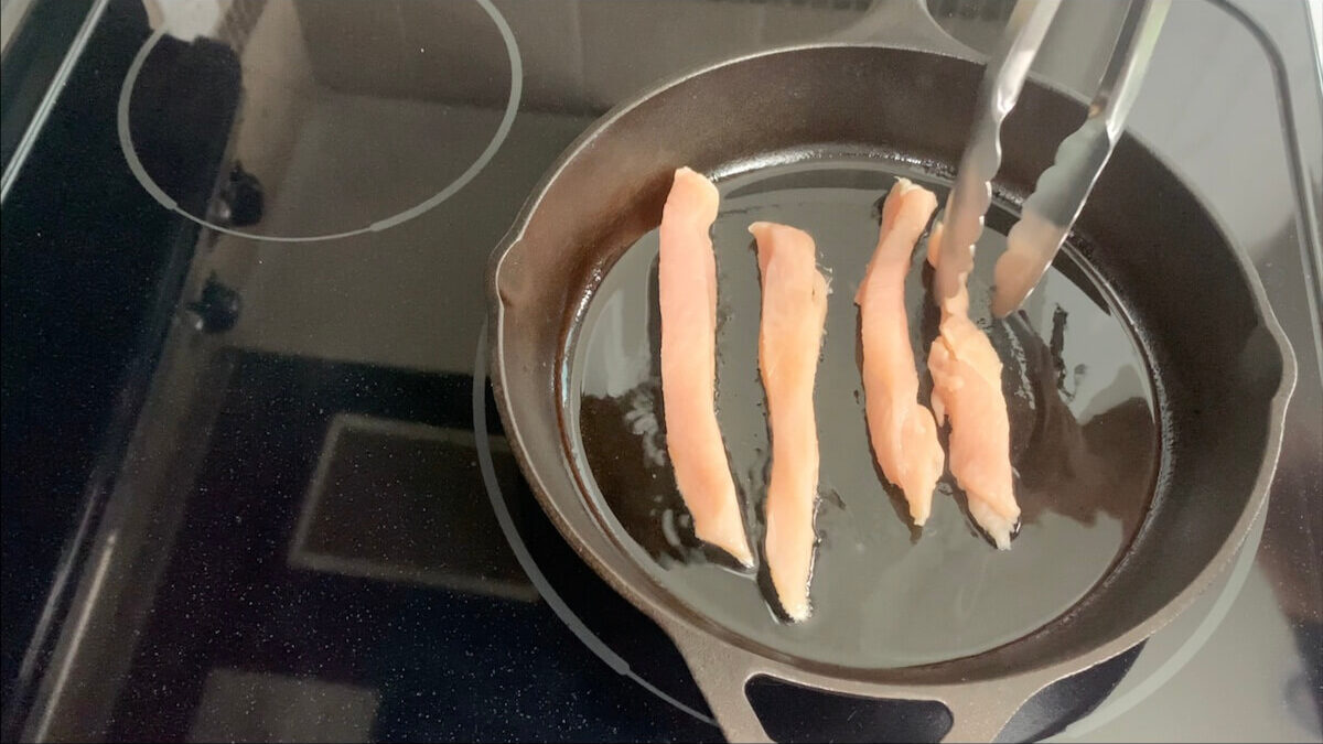 Add chicken strips to the skillet in a single row and cook on medium heat.