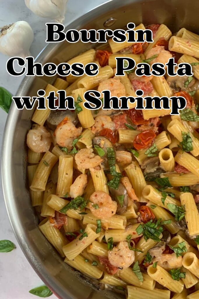 Boursin cheese pasta with shrimp vertical pic.  Shown in a pan with garlic bulbs and basil leaves in the background.