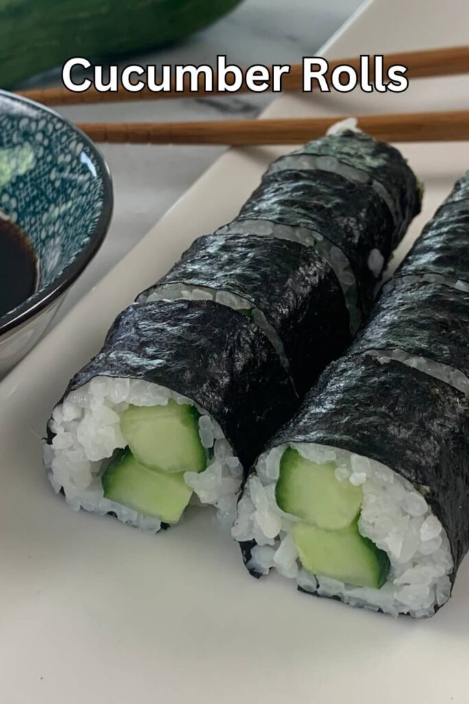 Cucumber roll (Kappa Maki) vertical photo on a white sushi platter.  Background includes chopsticks, soy sauce, and a cucumber.