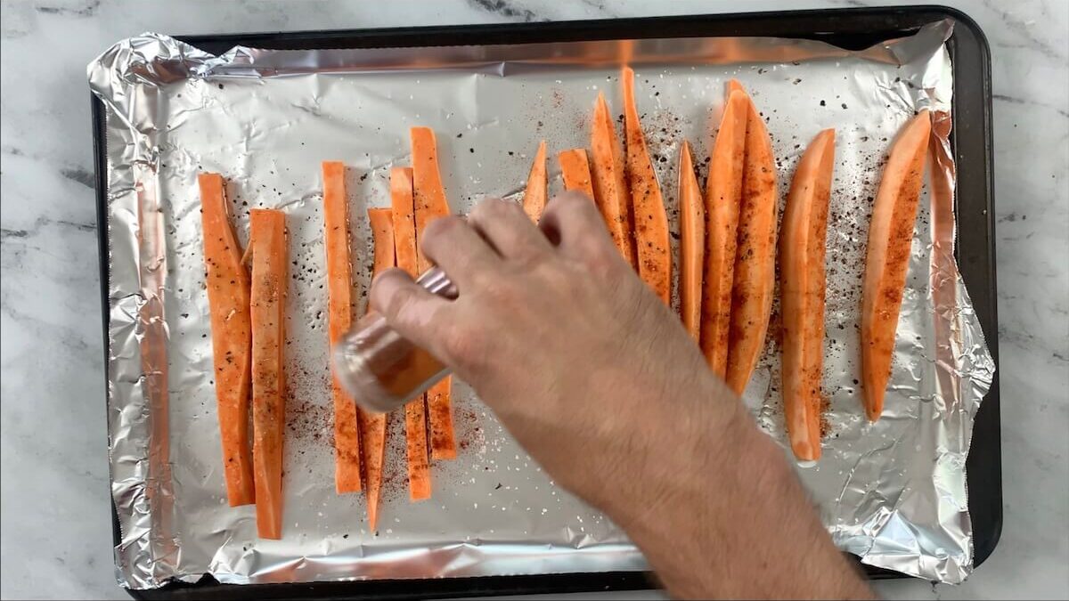 Season the sweet potato strips with salt, pepper, and paprika.