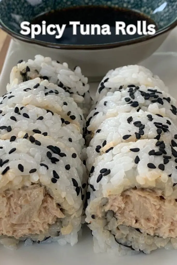 Spicy Tuna rolls arranged on a white sushi platter with a ramekin of soy sauce in the background.