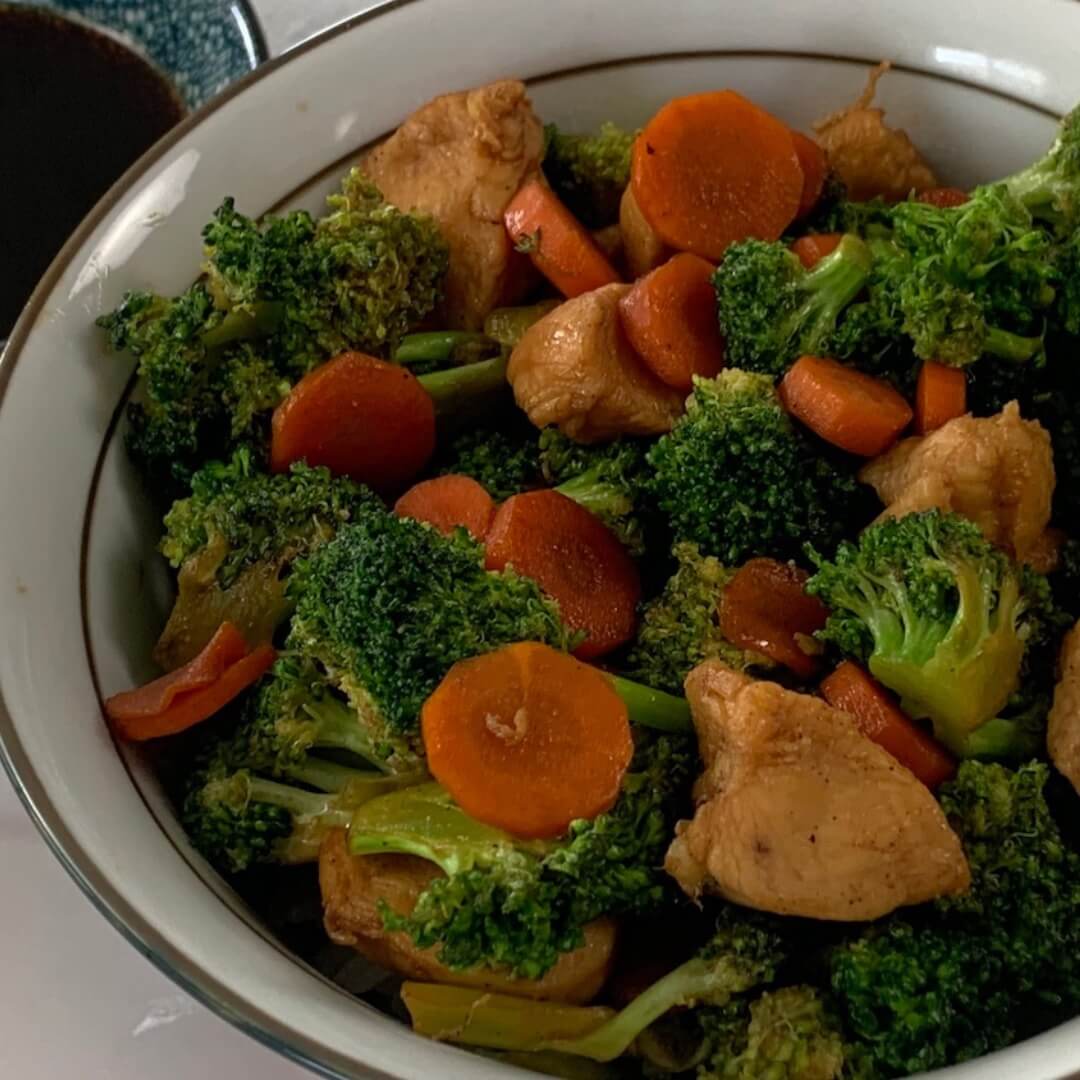 Chicken teriyaki bowl square pic with a ramekin of teriyaki sauce and chopsticks in the background.