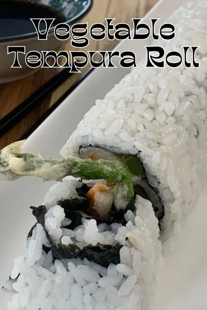 Vegetable tempura roll vertical pic on a white plate with chopsticks and a ramekin of tempura sauce in the background.