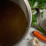 Beef broth square pic with parsley, carrots, and garlic in the background